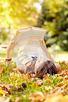 Reading, book and woman relax in park with novel in nature learning for education as student outdoor on campus