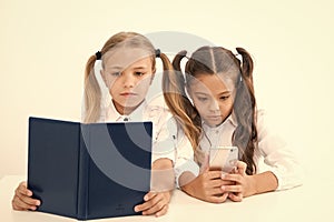 Reading concept. Getting information. Little girls reading paper book and ebook in smartphone. The right choice