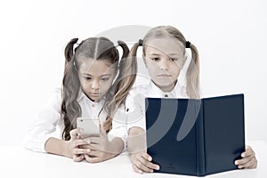 Reading concept. Getting information. Little girls reading paper book and ebook in smartphone. The right choice