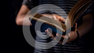 Reading Concept. Person Holding Opened Bible Book on Hand. Dark Tone