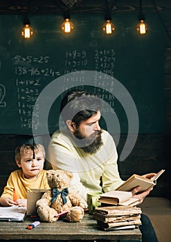 Reading concept. Teacher reading book to school boy. Little child listen to man reading book in class. Keep reading