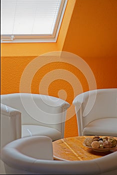 reading corner with white cocktail armchairs and orange woodchip walls