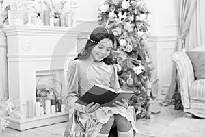 Reading days of Christmas. Cute little girl read book at Christmas tree. Adorable small child enjoy reading xmas story