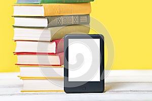 Reading. E-book reader and a stack of books on a yellow background. Mock up. Concept of education and electronic gadgets