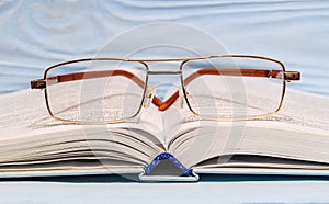 Reading eyeglasses lie on an open book closeup. Concept of reading habit or studying