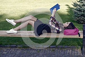 Reading is fun. Happy child read book lying on park bench. School library. Imagination and fantasy. Literacy education