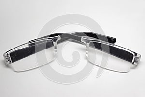 Reading glasses with black plastic eyeglass temples. transparent frame broken in half along the bridge between the lenses