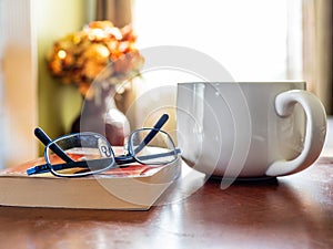 Reading glasses with book and coffee on table