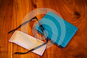 Reading Glasses and electronic reader on wooden table .