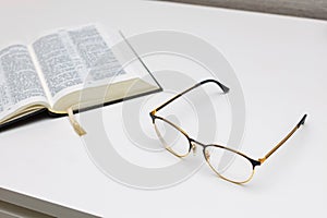 reading glasses lie on the table near the book