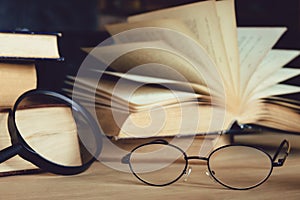 Reading glasses and magnifying glass with olds book on table