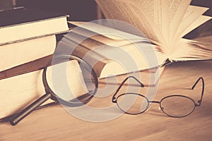 Reading glasses and magnifying glass with olds book on table photo