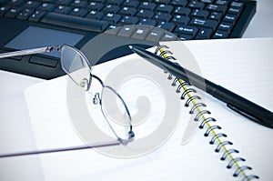 Reading glasses and pen on notebook