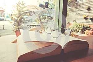 Reading glasses on table with open book