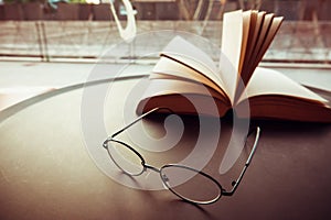 Reading glasses on table with open book