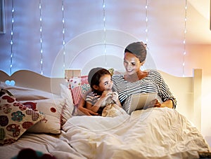 Reading her a bedtime story. Shot of an attractive young pregnant woman reading her daughter a bedtime story on a tablet