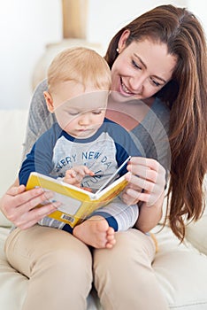 Reading his favourite book. a mother reading a book to her baby boy at home.