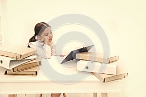 Reading makes her feel bored. Adorable pupil develop reading skills. Schoolgirl reading school book at desk. Little girl