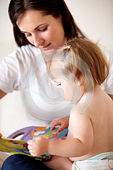 Reading with mom. A young mother showing her daughter pictures in a book.