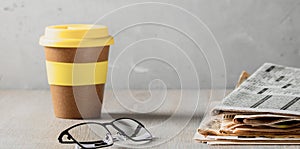 Reading the morning news. A stack of newspapers, glasses and glass of coffee on a wooden table