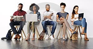 Reading the news in different ways. a group of diverse businesspeople waiting in line for an interview.