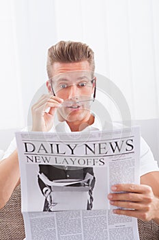 Reading Newspaper With The Headline New Layoffs