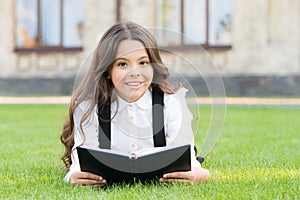 Reading is passport to world. Happy little girl enjoy reading book on green grass. Cute small child learn reading at