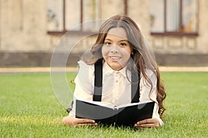 Reading is passport to world. Happy little girl enjoy reading book on green grass. Cute small child learn reading at