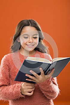 Reading practice for kids. Girl hold book read story over orange background. Child enjoy reading book. Book store