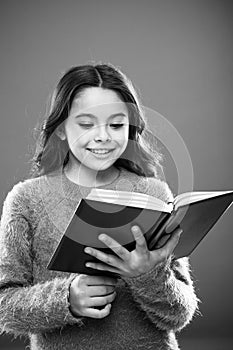 Reading practice for kids. Girl hold book read story over orange background. Child enjoy reading book. Book store