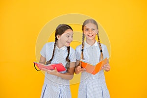 Reading and retelling. Small children holding books yellow background. Sincere interest. Little girls with encyclopedia