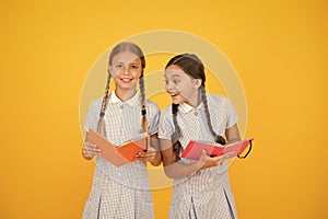 Reading and retelling. Small children holding books yellow background. Sincere interest. Little girls with encyclopedia photo