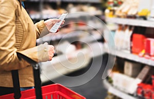 Reading shopping list in supermarket. Female customer.