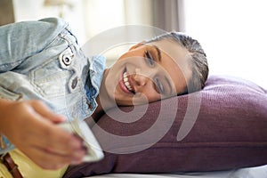 Reading an sms. an attractive young woman checking her cellphone while relaxing on her bed.