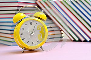 Reading time. Children`s books and an alarm clock. School knowledge.