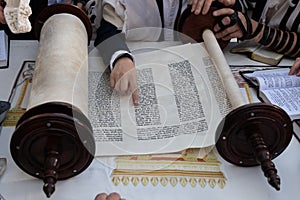 Reading the Torah scroll using a finger as a guide across the text