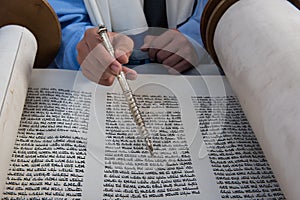 Reading from the Torah scroll using a silver pointer or yad