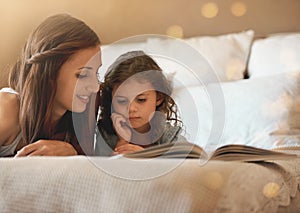 Reading is very important. a happy mother and daughter at home reading a storybook on the bed.