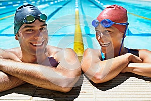 Ready for another lap. Two happy young swimmers standing in the pool smiling at the camera.