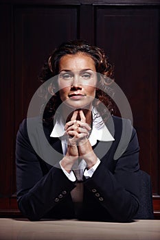 Ready for business. Mature advocate sitting with her hands clasped and facing the camera.