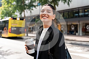 Ready for the day. Cheerful multiracial businesswoman in city street holding a thermo mug