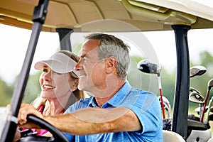 Ready for a game of golf. a couple riding in a golf cart on a golf course.