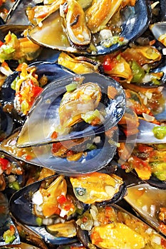 Ready mussel in the sink with vegetable salad. A plate of cooked mussels. Mussel shells lie on a plate