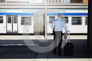 Ready for the next leg of his journey. Rearview shot of a businessman waiting for a bus at the bus station.