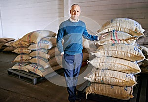 Ready for shipment. Portrait of a mature man standing by bags of coffee in a distribution warehouse.