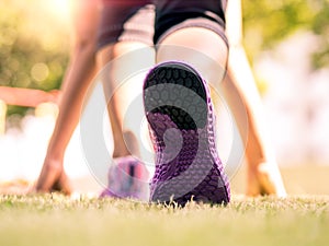 Ready steady go. Closeup of running shoes on grass, young lady on start position and going to run in park.