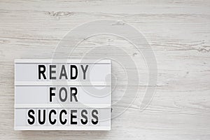 `Ready for success` words on a lightbox on a white wooden surface, top view. Overhead, from above, flat lay. Copy space