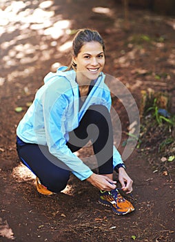 Ready to come second. Portrait of a woman tying up her running shoes before a trail run.
