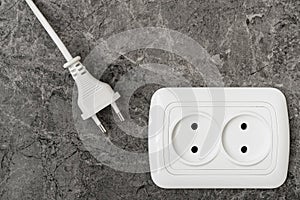 White power plug and electric socket on stone wall
