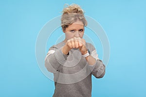 Ready to fight! Feisty woman with short curly hair in sweatshirt punching in front of camera, attacking and looking aggressively photo